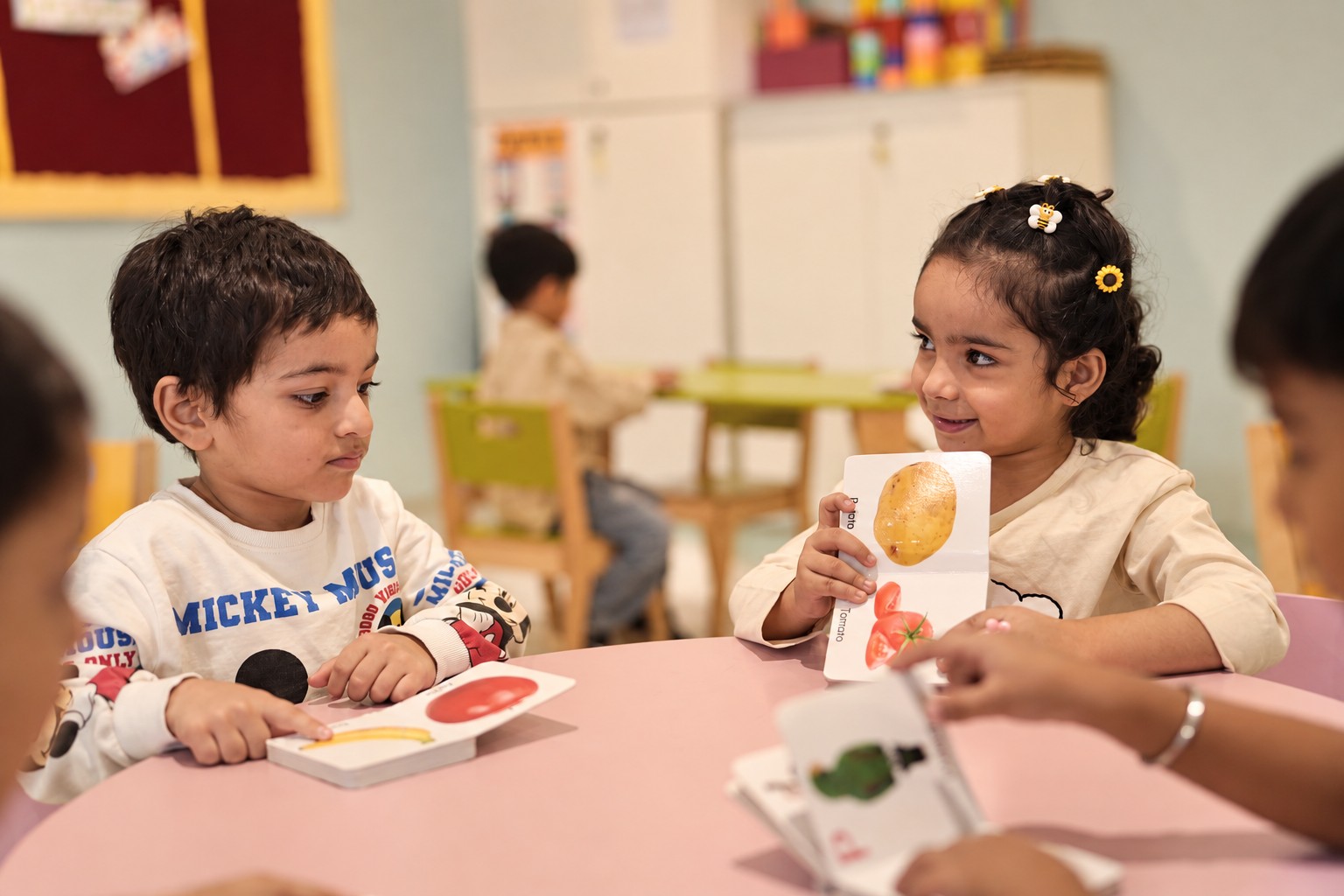 Children sharing picture cards at a round table