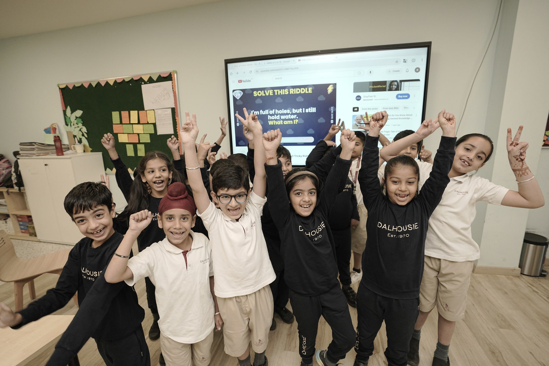 A class with their hands up after a riddle